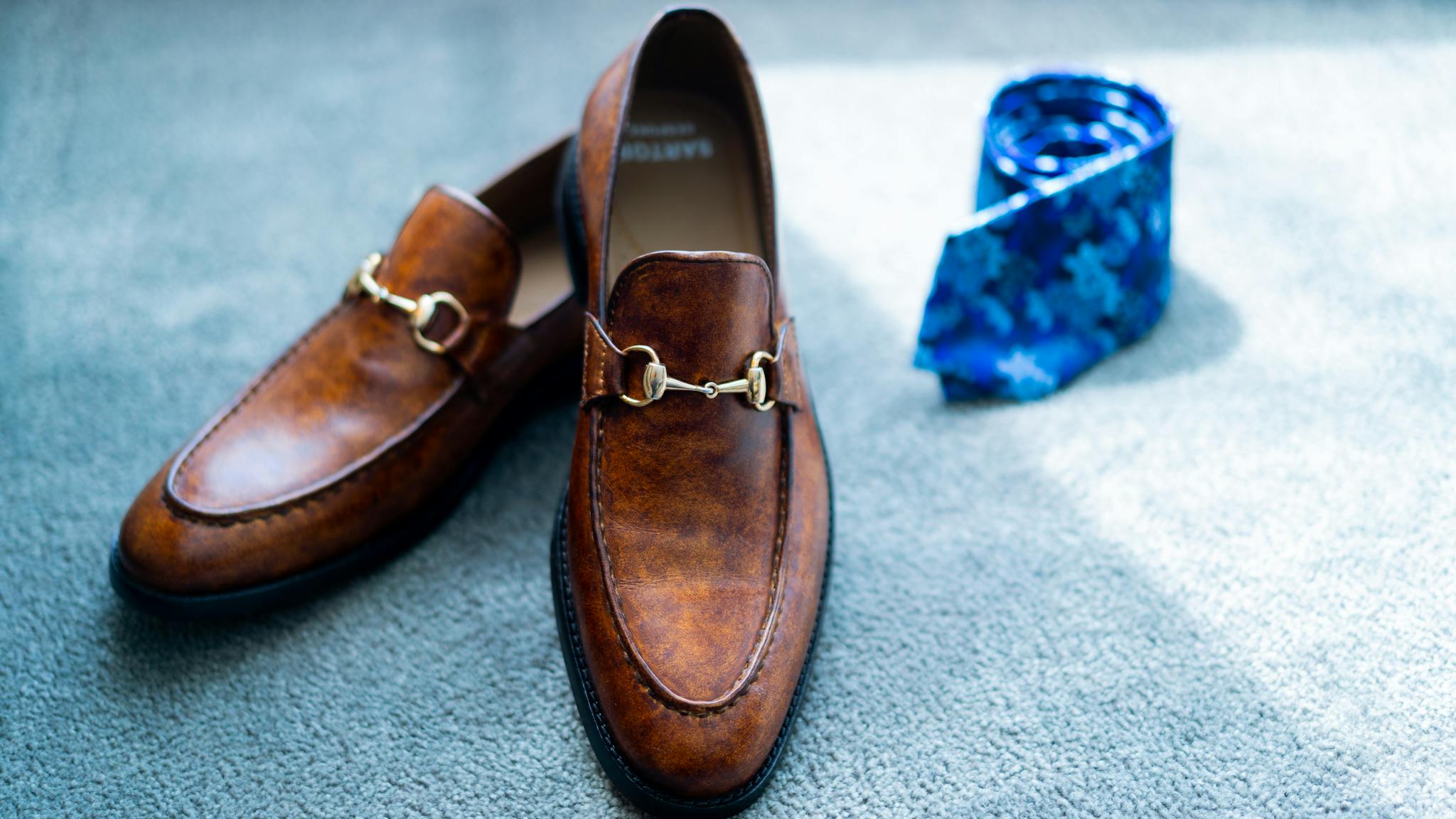 Classy brown shoes and tie placed on floor